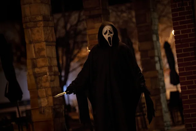 Ghostface beside the brick wall.