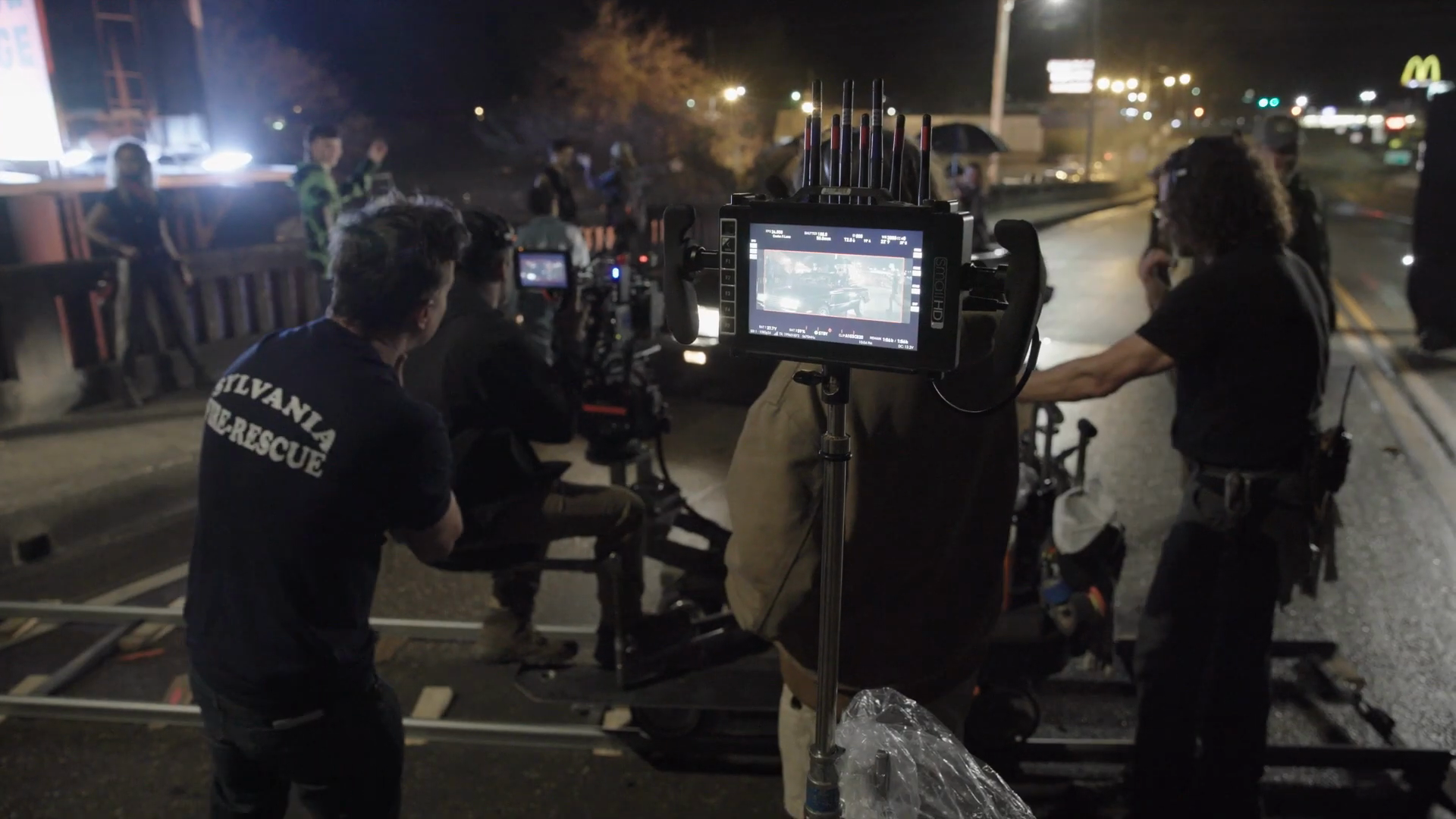Camera operators film beside the street procession.