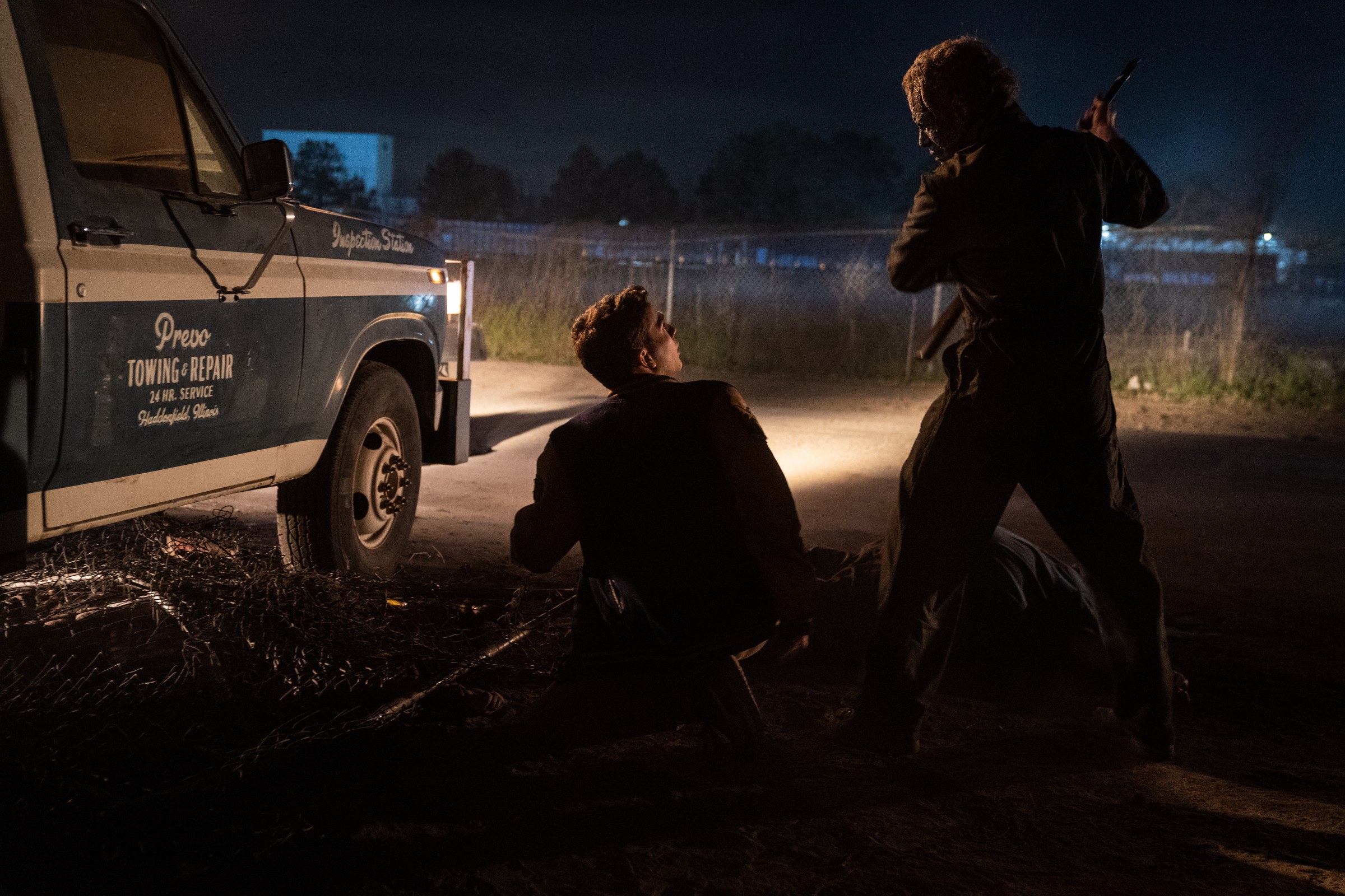 The masked attacker confronts Corey beside a truck at night.