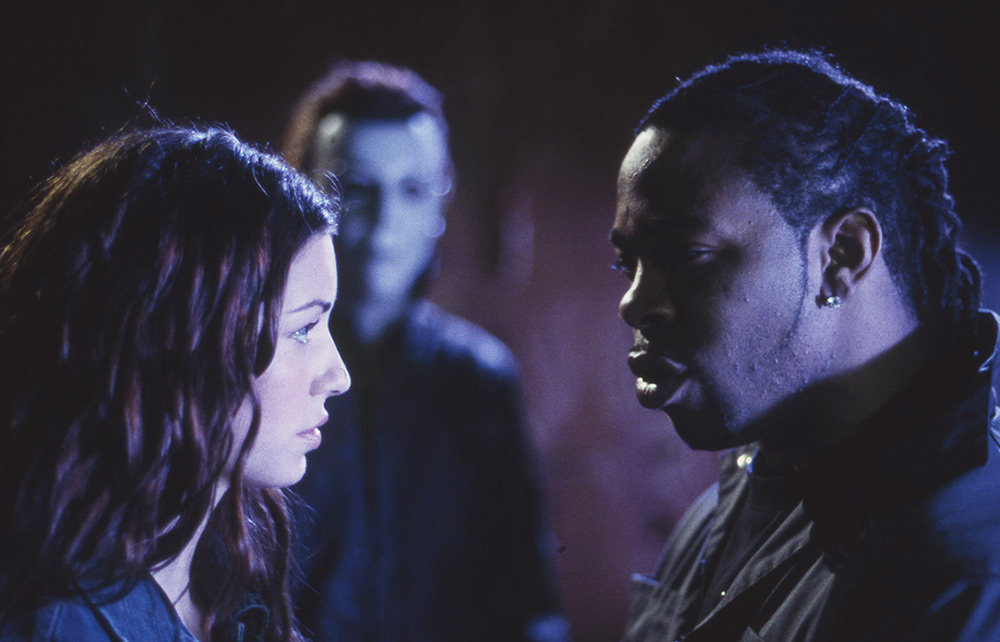 Sara and Freddie face one another with Michael Myers behind them.