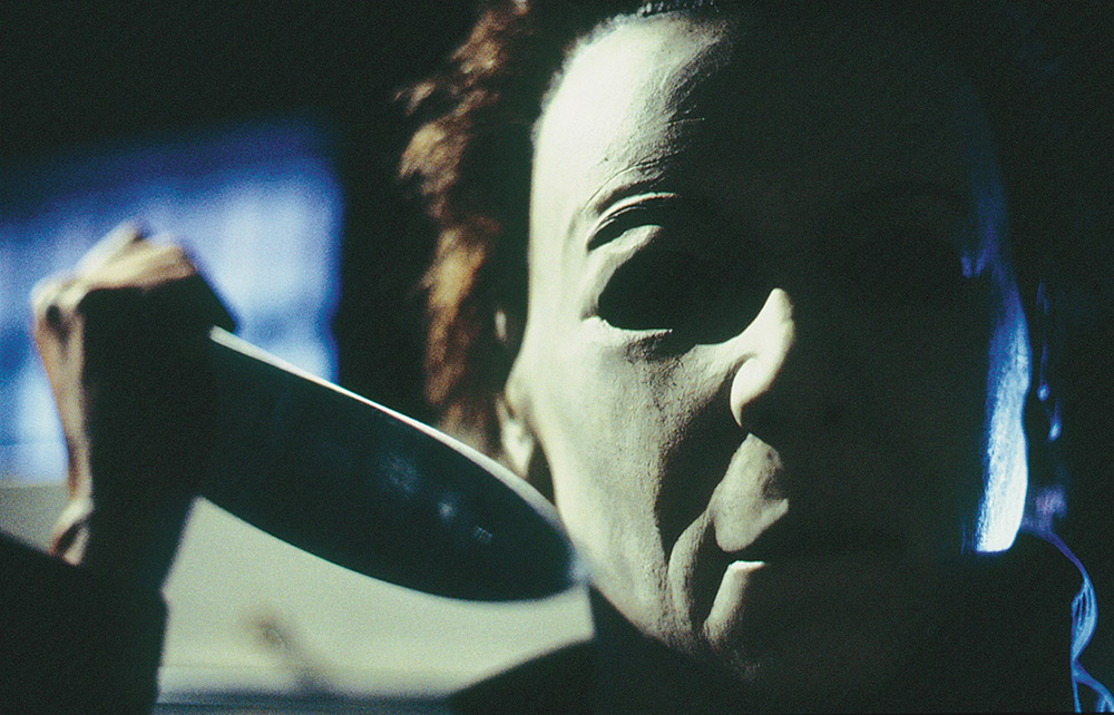 Michael Myers holds a knife beside his mask.