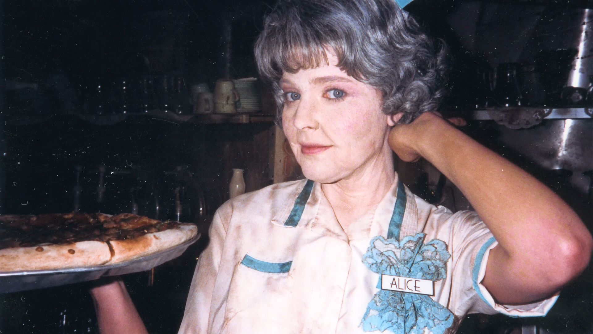 Lisa Wilcox waits with a pizza tray while an artist adjusts her aged-Alice wig.