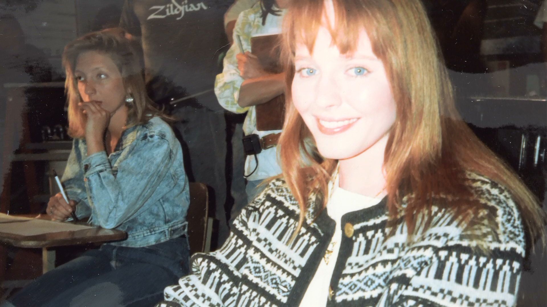 Lisa Wilcox smiling at a classroom desk between takes.