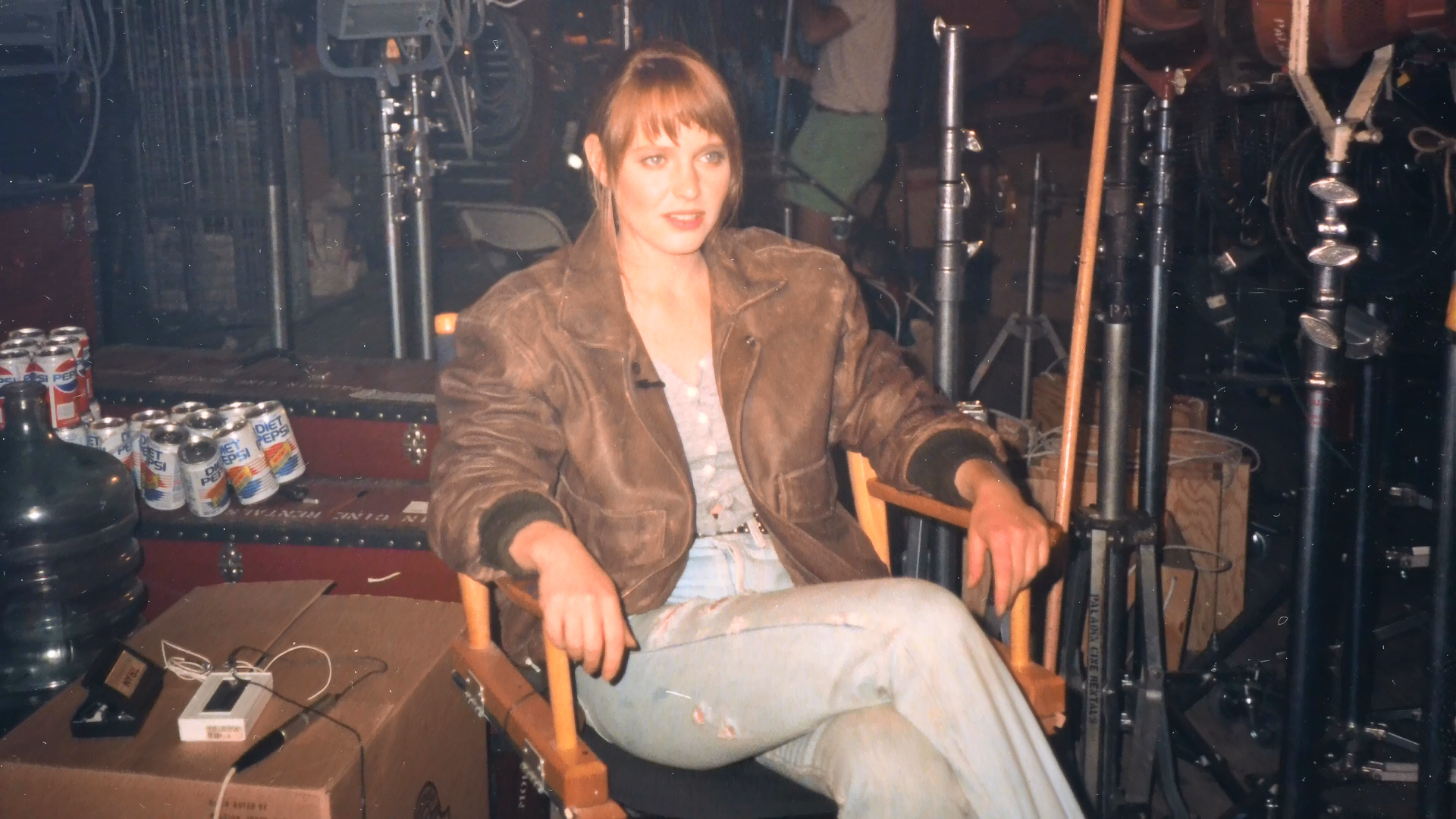 Lisa Wilcox seated beside lighting stands and production refreshments.