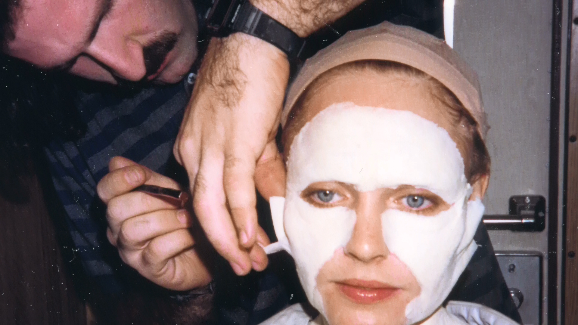 An artist applies the aged-Alice makeup around Lisa Wilcox's face.