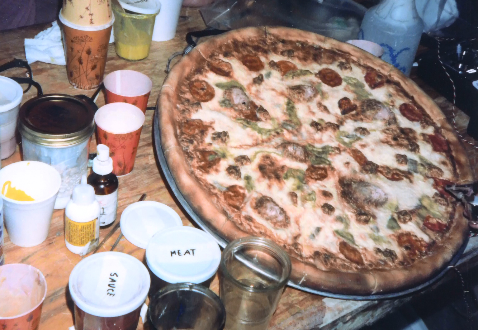 The effects pizza on a workshop table surrounded by paints and supplies.