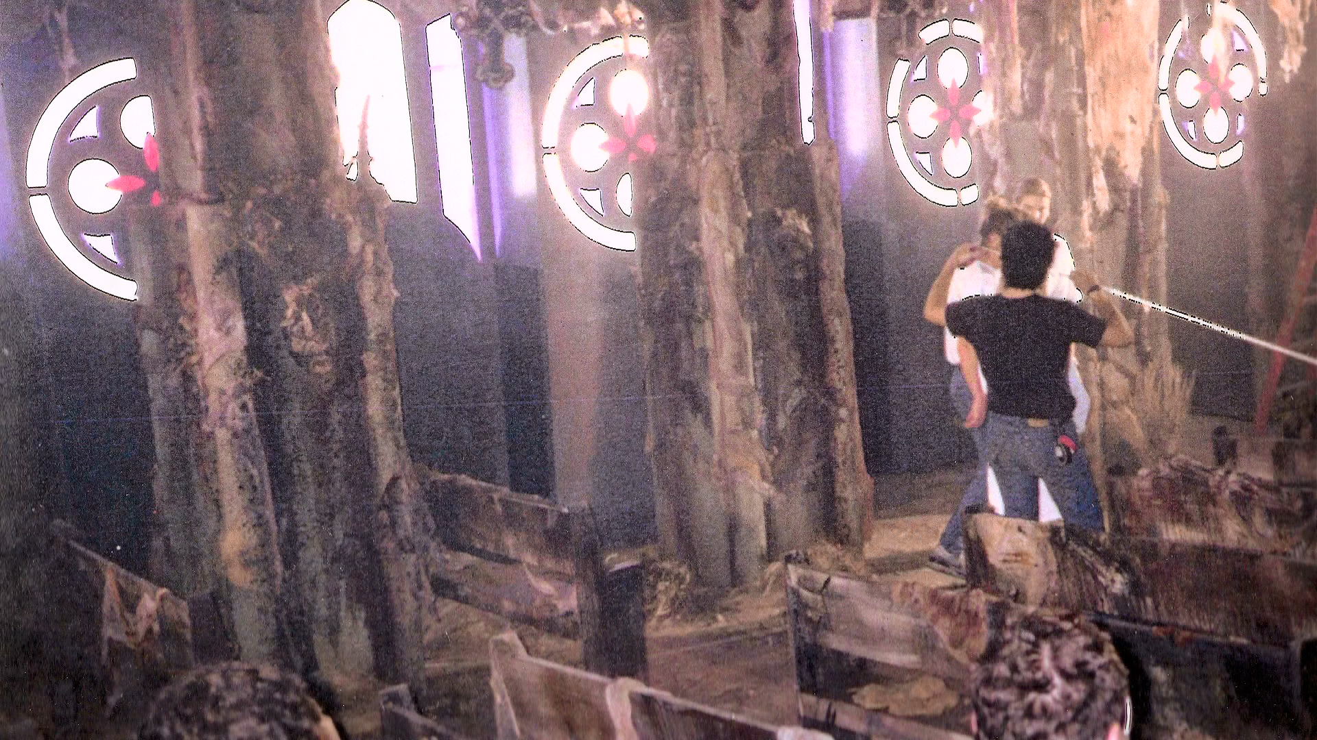 A crew member standing beneath the Gothic window during set preparation.