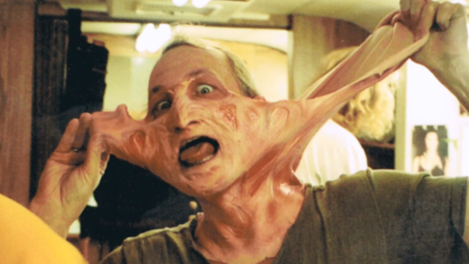 Robert Englund stretches loose appliance material during makeup removal.