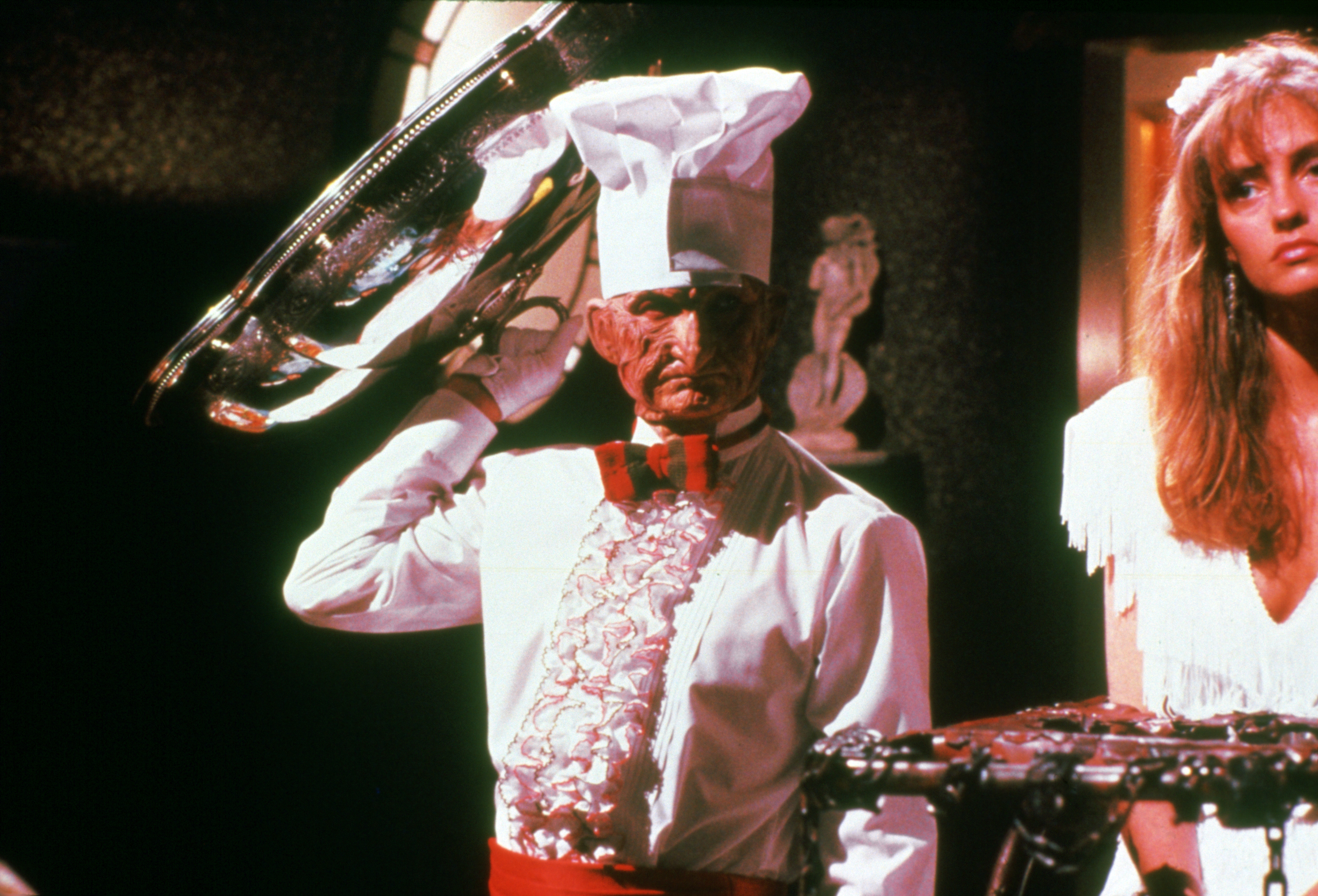 Freddy as a waiter beside Greta.
